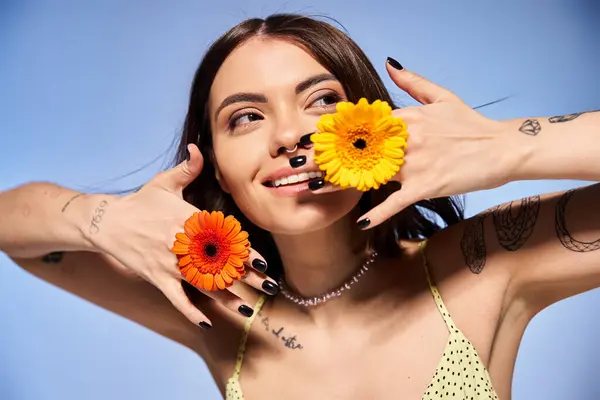 Eine junge Frau mit brünetten Haaren hält zwei Blumen vor ihr Gesicht, die natürliche Schönheit und Weiblichkeit demonstrieren. — Stockfoto