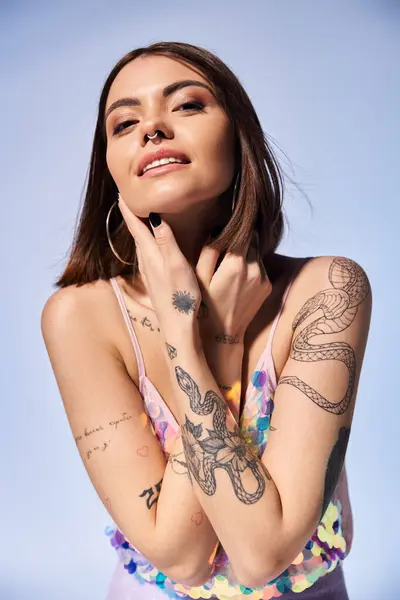 Una morena adornada con tatuajes posa en un estudio. - foto de stock