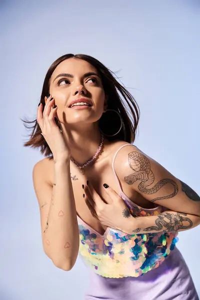 Uma jovem mulher com cabelo morena exibe orgulhosamente suas tatuagens detalhadas em seus braços e peito em um estúdio. — Fotografia de Stock