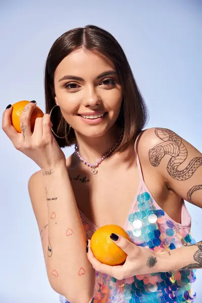 Una joven con el pelo moreno sosteniendo una naranja en una mano y una rodaja de fruta en la otra. - foto de stock