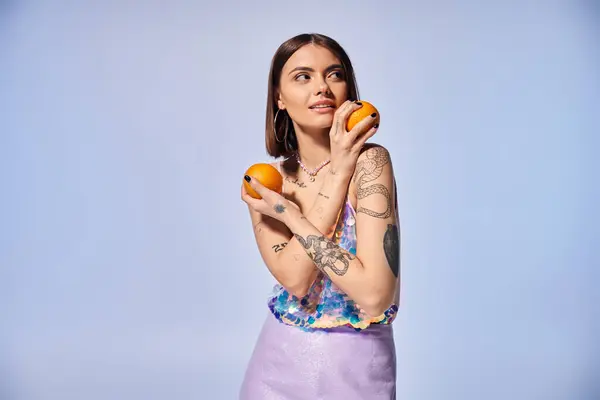 A young woman with brunette hair delicately holds two vibrant oranges in her hands. — Stock Photo