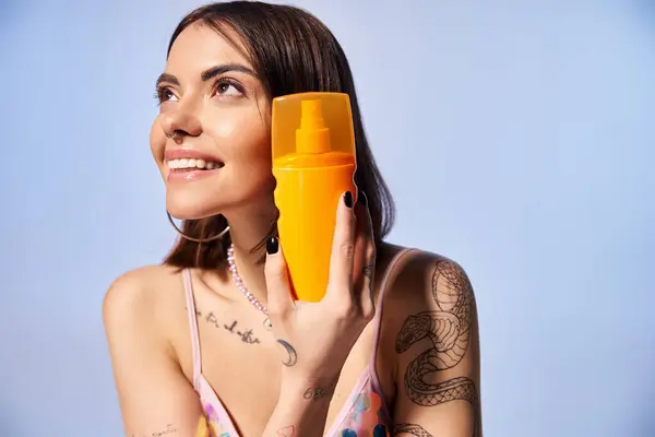 Молодая женщина с брюнетками держит желтую бутылку солнцезащитного крема. — стоковое фото
