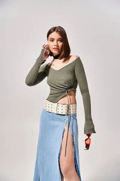 A young brunette woman gracefully dons a stylish skirt and cozy sweater in a studio setting. — Stock Photo