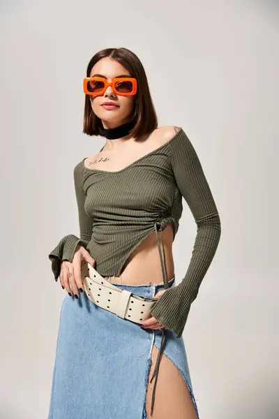 Eine brünette Frau mit Rock und Sonnenbrille posiert in einem Studio für ein Foto. — Stockfoto