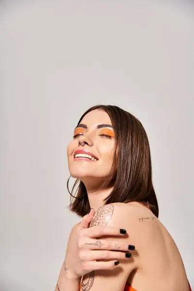 Una giovane donna con i capelli castani mostra un tatuaggio sul braccio in una posa elegante e sicura. — Foto stock