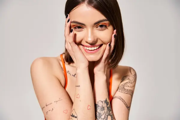 Une jeune femme aux cheveux bruns pose pour mettre en valeur ses tatouages en studio. — Photo de stock