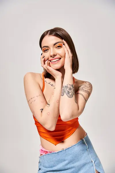 A stylish young woman with brunette hair strikes a pose to showcase her intricate tattoos in a studio setting. — Stock Photo