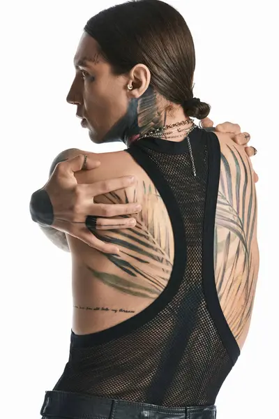 Молодий чоловік з детальним татуюванням на спині, демонструє артистичність та самовираження в студійній обстановці. — стокове фото