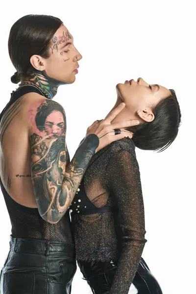 Молода татуйована пара стоїть пліч-о-пліч у студії, демонструючи своє складне мистецтво тіла на сірому фоні. — стокове фото