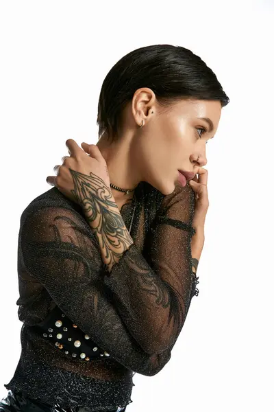 Молода жінка з вражаючим татуюванням, що обожнює її руку, стоїть в студії зі своїм партнером на сірому фоні. — стокове фото