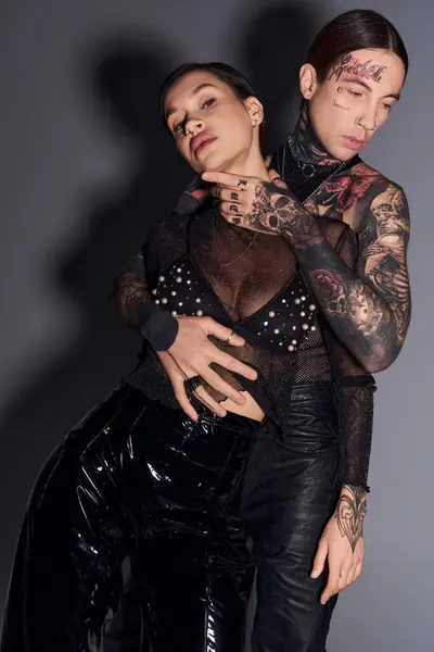 Un jeune couple tatoué se tient côte à côte dans un studio, mettant en valeur leur lien unique et leur individualité. — Photo de stock