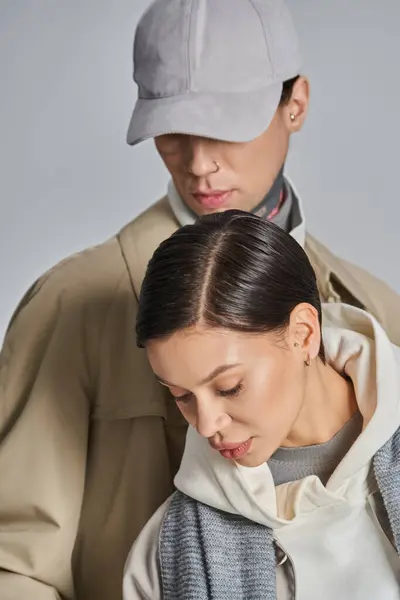 Una giovane coppia elegante in trench su sfondo grigio in ambiente studio — Foto stock