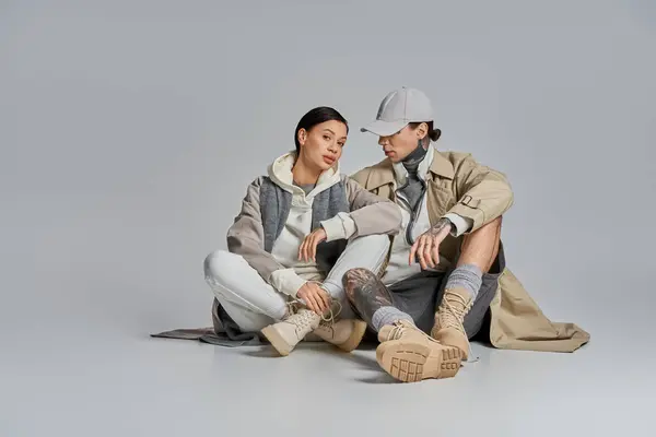 Ein Mann und eine Frau in stilvoller Kleidung sitzen zusammen auf dem Boden und führen ein tiefgreifendes Gespräch oder einen Moment der Verbindung.. — Stockfoto