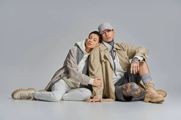 A stylish young woman in a trench coat sitting on the ground with her partner, enjoying a moment of togetherness — Stock Photo