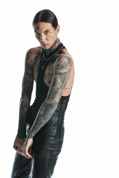 Молодий чоловік з вражаючим татуюванням на руці впевнено стоїть у студійній обстановці. — стокове фото