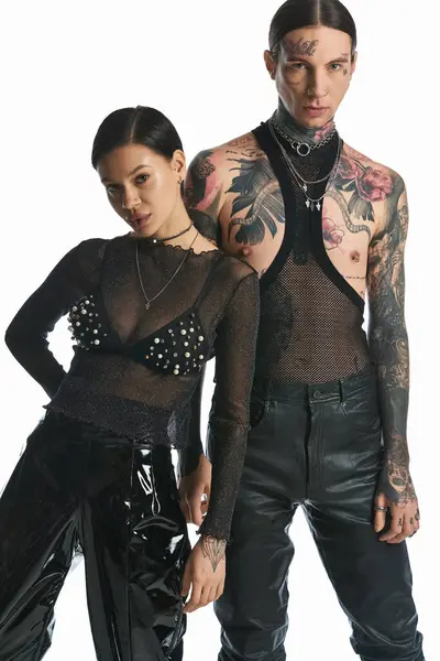 A young, tattooed man and woman standing together in a studio on a grey background. — Stock Photo