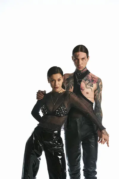 Un hombre joven y una mujer elegantes y tatuados se unen en un estudio, mostrando su aspecto y conexión únicos. - foto de stock