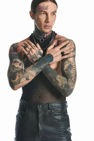 Молодий чоловік з татуюваннями на руках і грудях в студії на сірому фоні, демонструє своє унікальне мистецтво тіла. — стокове фото
