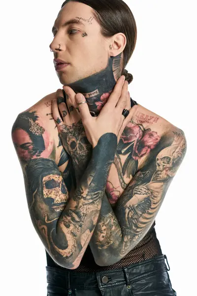 A young man with intricate tattoos adorning her chest and neck poses elegantly in a studio against a grey background. — Stock Photo
