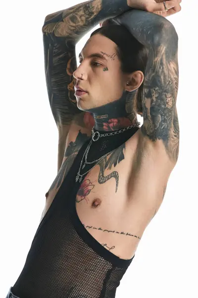 Стильний молодий чоловік з гордістю демонструє складні татуювання на руці та грудях, виключаючи художнє вираження та індивідуальність. — стокове фото