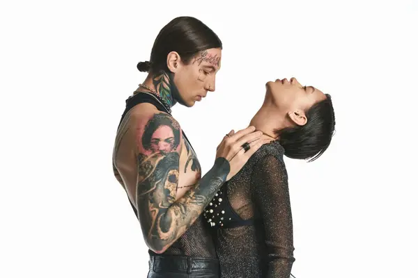 A young stylish and tattooed couple standing close together in a studio against a grey background. — Stock Photo