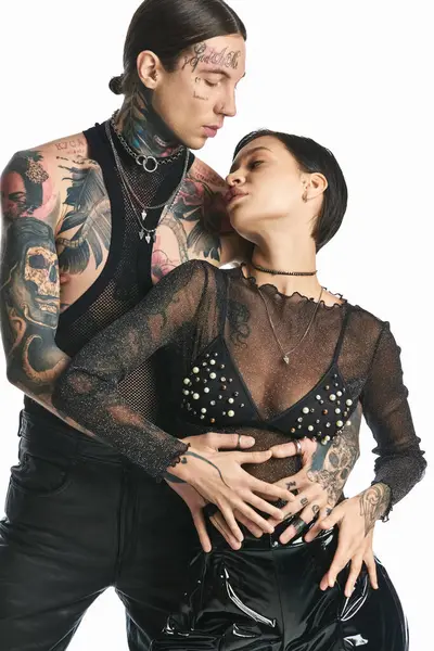 Un jeune couple élégant, orné de tatouages, posant pour une photo dans un studio sur un fond gris. — Photo de stock