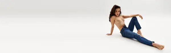 A captivating, bare woman gracefully seated on the floor. — Stock Photo