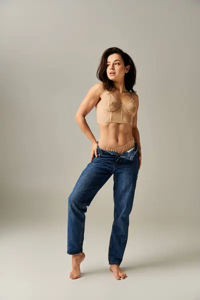 Uma jovem bate uma pose sensual em um top de sutiã e jeans. — Fotografia de Stock