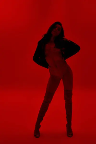 Молода жінка в нижній білизні стоїть впевнено в яскравій червоній кімнаті з руками на стегнах. — стокове фото