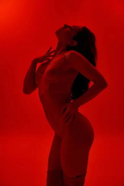 Femme en lingerie frappant une pose confiante avec les mains sur les hanches dans une salle rouge vibrante. — Photo de stock