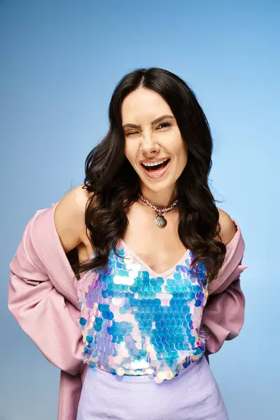 Eine atemberaubende Frau trägt ein lila Oberteil und lächelt fröhlich in einem Studio mit leuchtend blauem Hintergrund. — Stockfoto