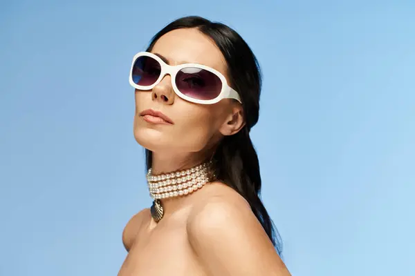 A stylish and pretty woman striking a pose in sunglasses and a choker against a vibrant blue background, exuding summertime vibes. — Stock Photo