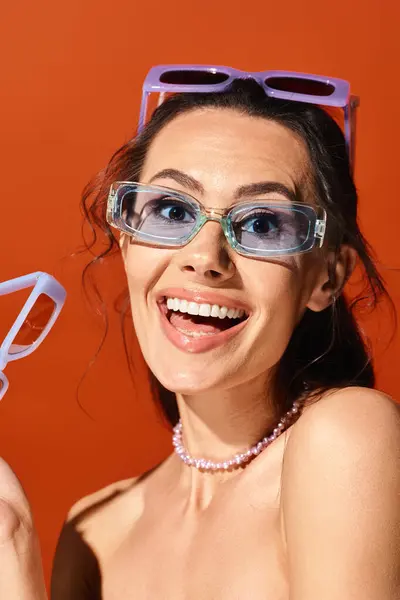 Une femme à la mode portant des lunettes sur un fond orange. — Photo de stock