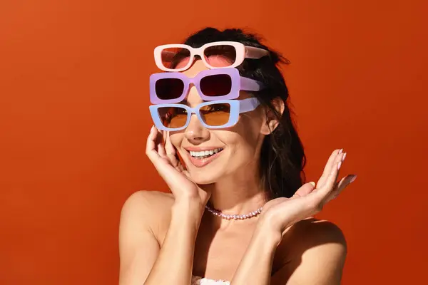 Стильная женщина в солнечных очках позирует в студии на оранжевом фоне. — стоковое фото