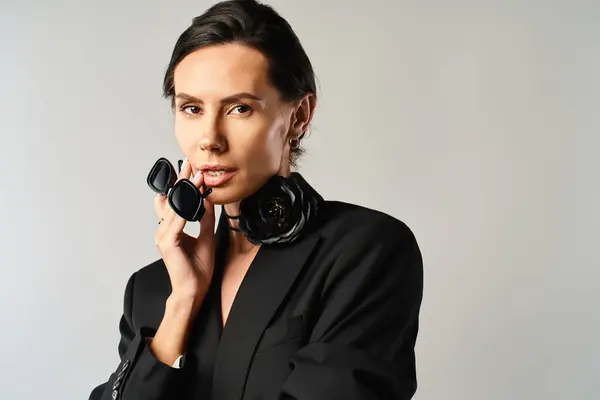 A stylish woman in sunglasses confidently poses in a sleek black suit — Stock Photo
