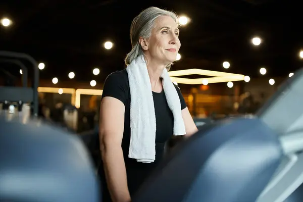 Good looking merry senior sportswoman in cozy t shirt exercising actively on treadmill in gym — Stock Photo