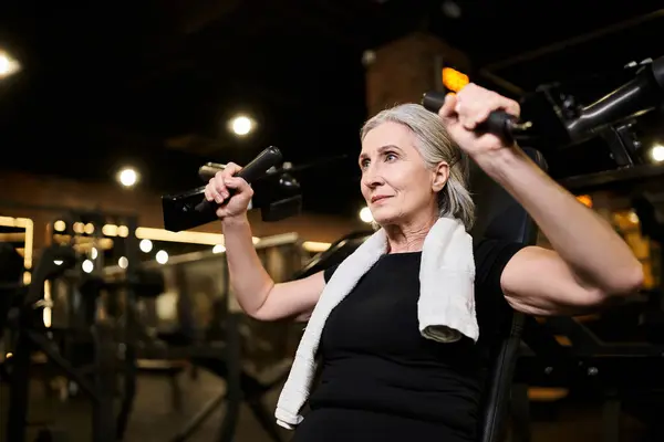 Sporty mature beautiful woman in cozy attire exercising actively on chest press machine in gym — Stock Photo