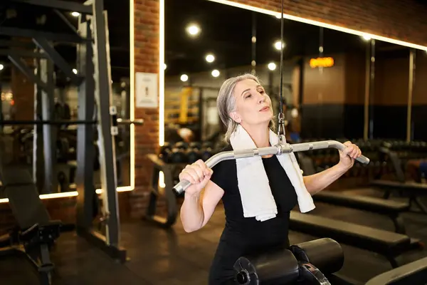 Attraktive sportliche reife Frau im gemütlichen Outfit, die aktiv mit Lats-Pulldown-Gerät im Fitnessstudio trainiert — Stockfoto