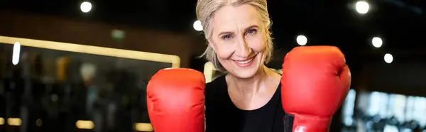 Fröhliche reife Frau in Sportbekleidung mit Boxhandschuhen, die am Ring trainiert und in die Kamera lächelt, Banner — Stockfoto