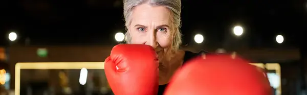 Felice donna anziana in abbigliamento sportivo con guanti da boxe allenamento sul ring e sorridente alla macchina fotografica, banner — Foto stock
