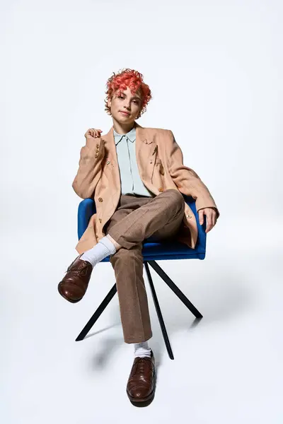 Femme extraordinaire aux cheveux roux s'assoit confortablement sur une chaise bleue. — Photo de stock