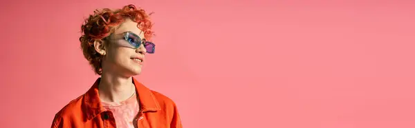 Eine elegante Frau mit roten Haaren trägt Sonnenbrille vor leuchtend rosa Hintergrund. — Stockfoto