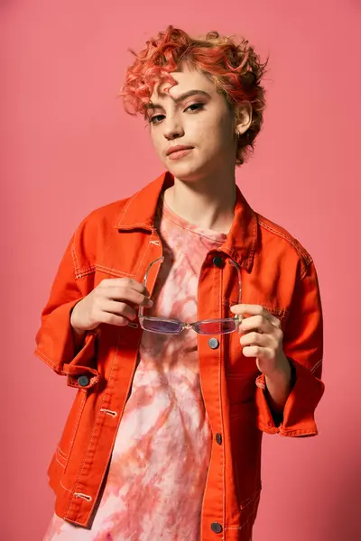 Stylish woman in orange shirt gracefully holding glasses. — Stock Photo