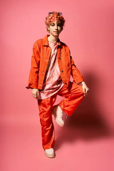 Экстравагантная женщина выделяется в оранжевой куртке и красных штанах. — Stock Photo