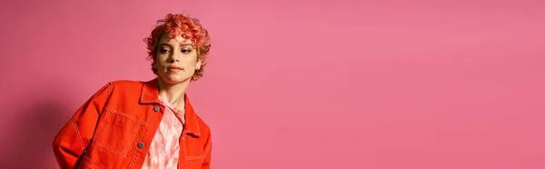 A woman with red hair poses in front of a pink wall. — Stock Photo