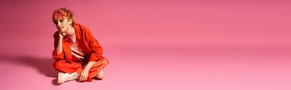 Extraordinary woman sitting gracefully on pink surface with matching background. — Stock Photo