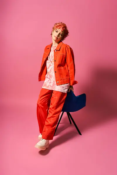A graceful woman sits on a chair against a vivid pink backdrop. — Stock Photo