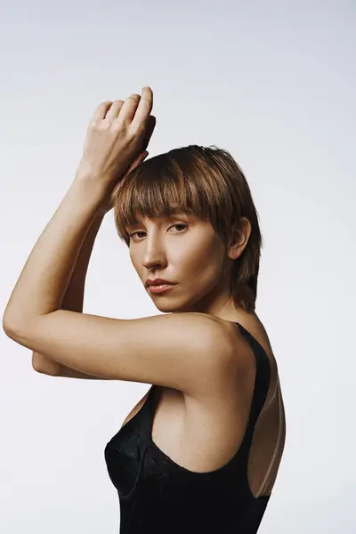 A chic young woman confidently posing in a fashionable black swimsuit. — Stock Photo