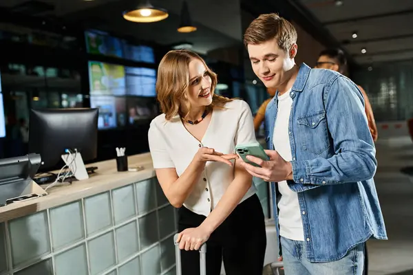 A man and woman, colleagues on a corporate trip, stand together in a hotel lobby. The man holds a cell phone. — Stock Photo