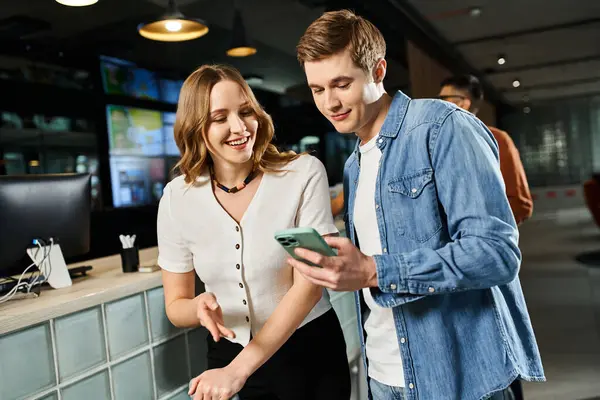 A man and a woman, colleagues, engrossed in a cell phone screen while in a hotel lobby during a corporate trip. — Stock Photo